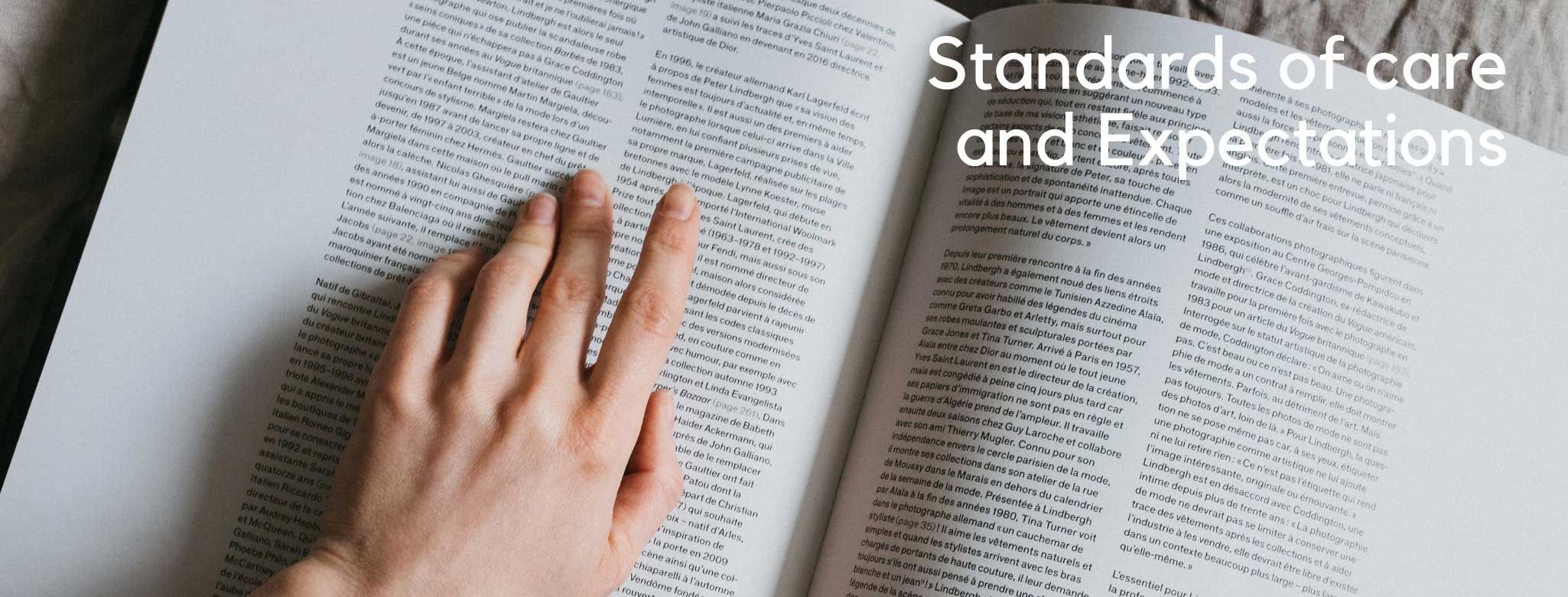 a small hand skimming down a page of a large book