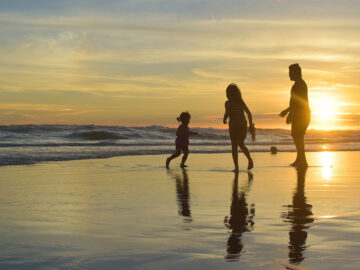 Family playing on a beach as the sun is going down