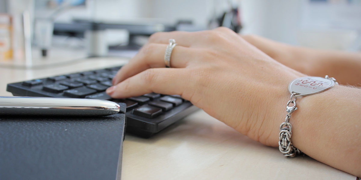 Woman with an asthma bracelist typing on a keyboard
